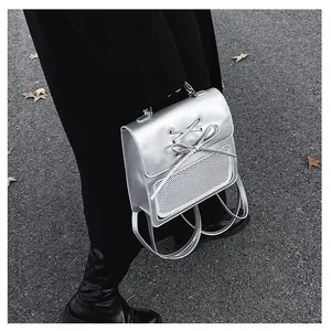 Detail of silver metallic backpack featuring lace-up bow and black mesh pocket
