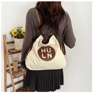 Detail of the white canvas tote with adjustable brown leather straps and HULN logo patch