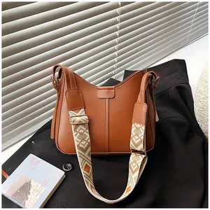 Brown leather crossbody bag detail featuring a wide bohemian geometric strap on a blazer