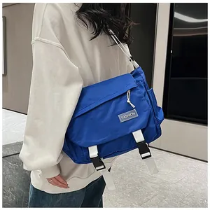 Side view of blue nylon messenger bag with white strap and fashion label on a model
