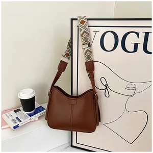 Detail of brown PU leather hobo bag with vintage geometric patterned wide strap