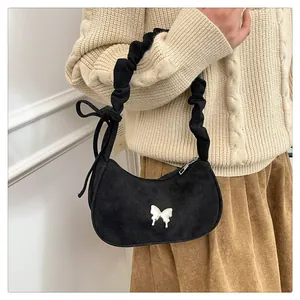 Detail of black suede underarm bag with silver butterfly buckle and scrunchie handle