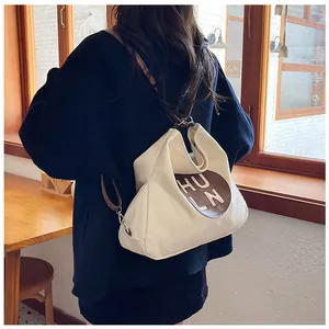 Close-up of off-white canvas tote bag with brown leather patch and shoulder strap