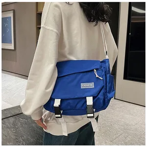 Detailed view of royal blue nylon messenger bag with fashion label and white straps