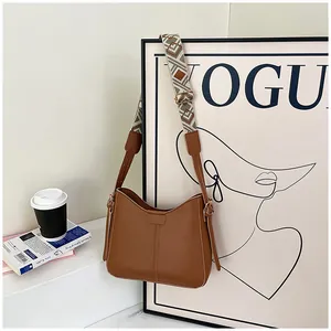 Detail of a brown shoulder bag featuring a wide geometric woven strap on a Vogue background