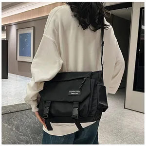 Detail of black nylon messenger bag with side buckle straps and fabric label patch
