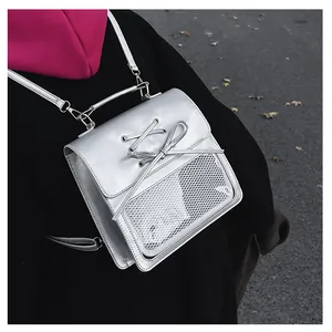 Detailed view of silver metallic backpack with ribbon lacing and transparent mesh pocket