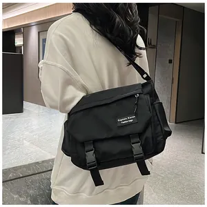 Detail of black nylon messenger bag with adjustable strap and plastic buckles on model