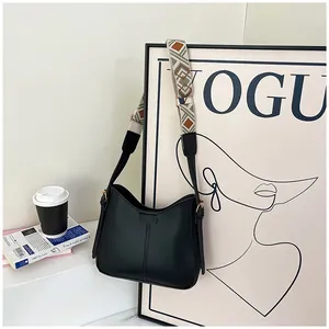 Detail of minimalist black hobo bag with ethnic geometric wide shoulder strap