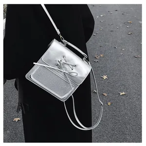 Detail of silver metallic crossbody bag with lace-up design and white mesh panels