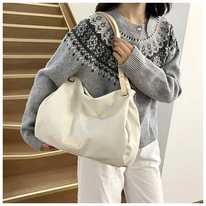 Detail of a large white tote bag with leather strap and metal buckle worn by a model