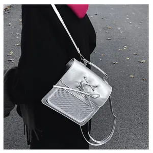 Metallic silver backpack with ribbon detail and white mesh pocket in outdoor setting