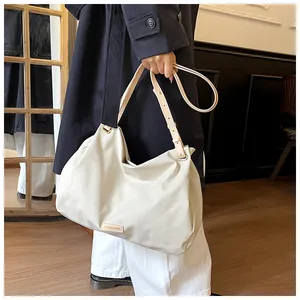 Detail of the adjustable shoulder strap and metal logo on the ivory oversized tote bag