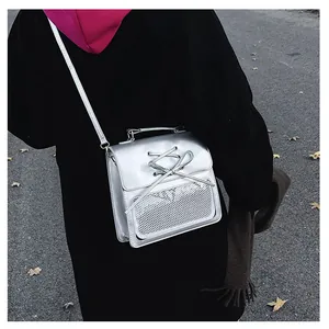 Detail view of a silver PU leather crossbody bag featuring bow ties and a mesh pocket