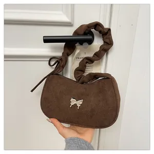 Detail of a dark brown suede underarm bag with silver butterfly and pleated handle