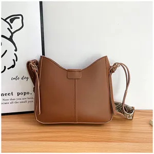 Detail of a brown shoulder bag with vertical stitching and geometric jacquard strap