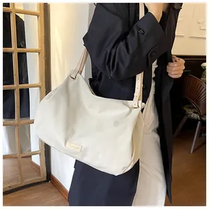 Detailed view of cream leather tote bag with elegant metallic brand tag and shoulder strap