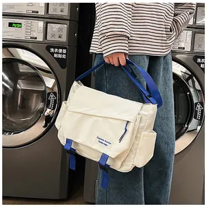 Detail of off-white messenger bag featuring blue contrast straps and buckle closures