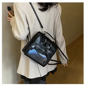 Detail of black crossbody ita bag featuring lace-up design and clear PVC window on model