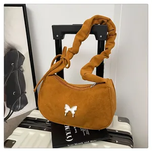 Detail of a brown suede crescent bag featuring silver butterfly hardware and ruched strap