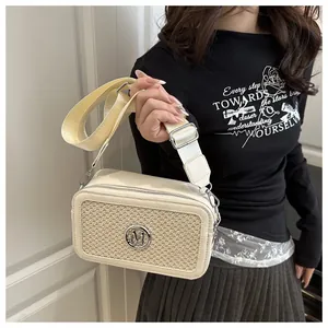 Detail of cream crossbody bag featuring woven texture and round metallic M logo