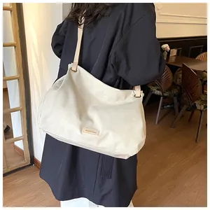 Close-up of beige leather tote bag with branded metal logo plate and fine stitching