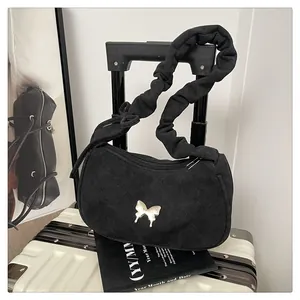 Close-up of black crossbody bag with silver butterfly emblem and ruffled shoulder strap