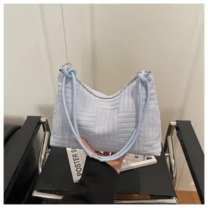 Détail du sac à bandoulière en velours bleu clair avec texture tissée et anneaux métal