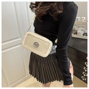 Detail of white woven crossbody bag with metal M logo and stylish wide shoulder strap