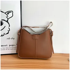 Detail of caramel leather shoulder bag featuring vertical stitching and woven geometric strap