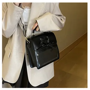 Detail view of black glossy leather ita bag with bow straps and transparent window