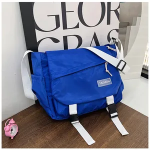 Close-up of royal blue nylon messenger bag with white strap and fashion label on desk