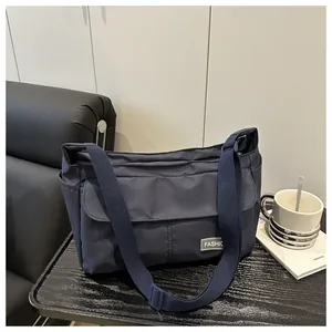 Detail shot of navy blue crossbody bag with white fashion label on a leather sofa