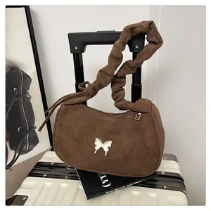 Close-up of brown suede moon bag with silver butterfly charm and ruched strap
