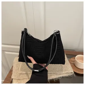 Gros plan sur le motif géométrique gaufré noir et la boucle en métal du sac à bandoulière
