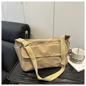 Detail of khaki nylon messenger bag with fashion label and adjustable strap on desk