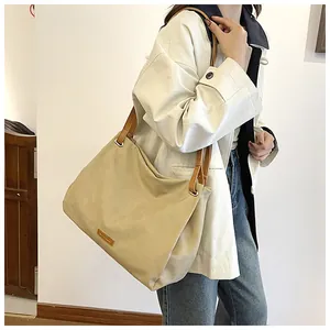 Close-up of a large beige canvas tote bag with brown leather straps for daily commuting