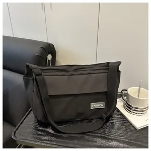 Detail of a black canvas messenger bag with a wide adjustable strap and fashion patch