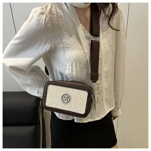 Close-up of a woven crossbody bag with leather trim and wide strap on a model