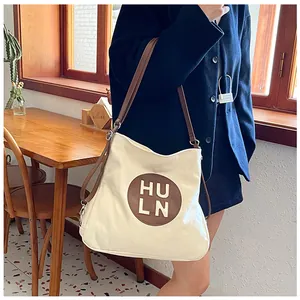 Detailed close-up of the large canvas tote bag with brown leather HULN logo and thin straps