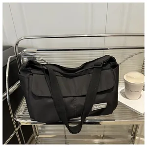 Detail of a black nylon messenger bag with fashion label on a modern chrome shelf