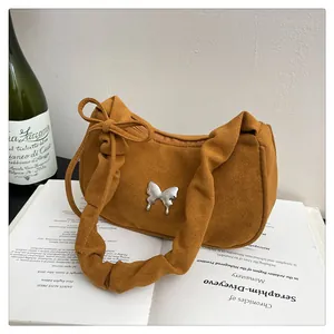 Detailed macro of brown suede shoulder bag with silver butterfly and pleated handle