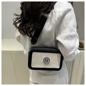 Detail of contrast weave texture and silver M logo on a stylish crossbody square bag