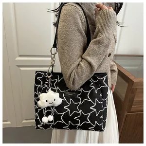 Detail showing star-patterned knit texture of the black and white tote bag with cloud charm