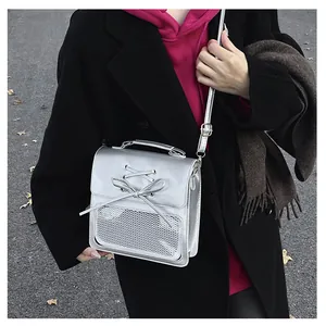 Silver metallic crossbody bag featuring bow detail and mesh pocket shown on model outdoors