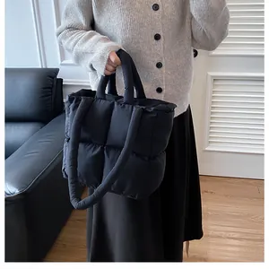 Detail view of the black quilted puffer tote bag with dual straps held by a model