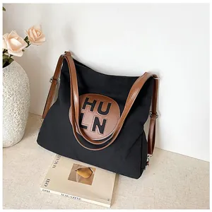 Detail of black canvas tote bag with HULN leather patch and brown adjustable straps