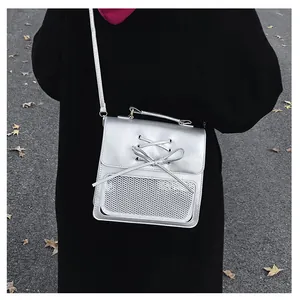 Silver PU leather ita bag with bow detail and white mesh pocket shown in a street view
