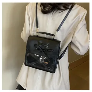 Rear view of a black ita bag backpack with clear window and bow detail on a beige blazer