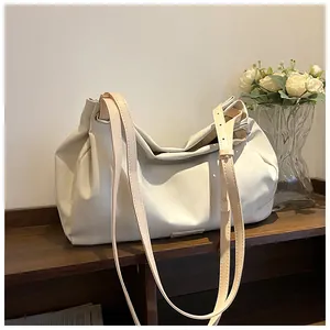 Close-up of the spacious cream-colored tote bag with slim brown shoulder straps on a desk